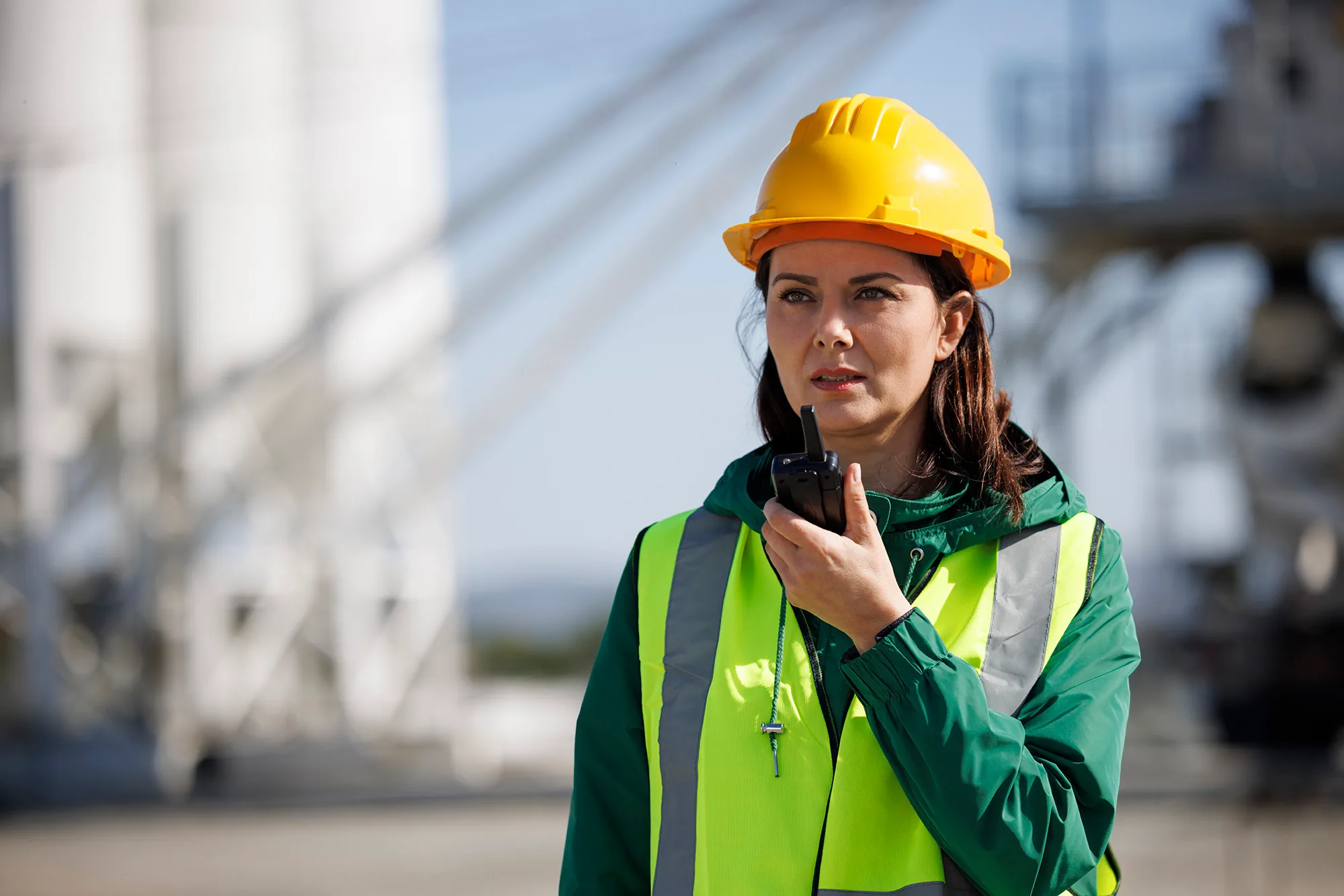 Portrait of a female engineer using walkie-talkie at industrial facility